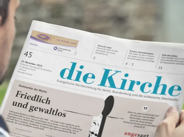 Ein Mann hält die evangelische Wochenzeitung ,,die Kirche'' in der Hand.