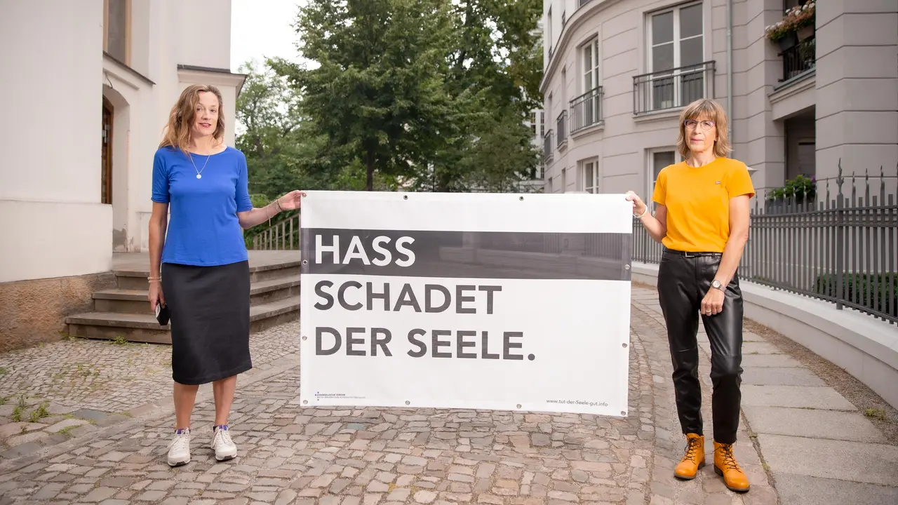 Zwei Frauen halten ein Plakat "Hass schadet der Seele".