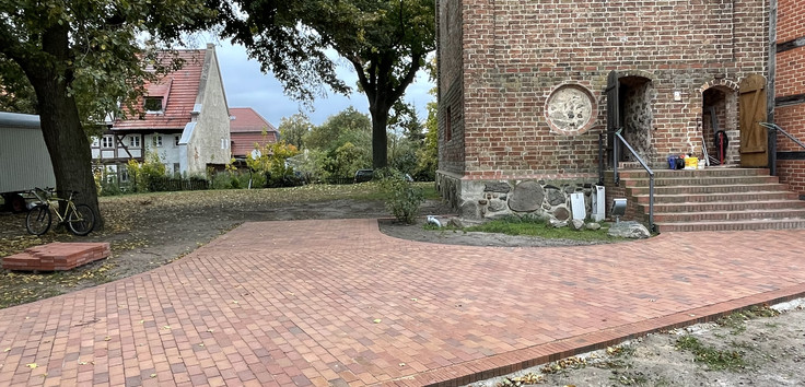 Man sieht den neu gestalteten Vorplatz der Dorfkirche in PEssin.