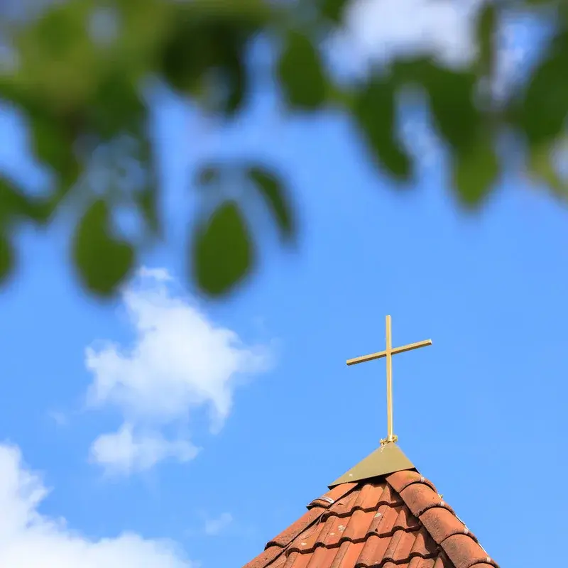 Blick gen Himmel auf ein Kreuz.