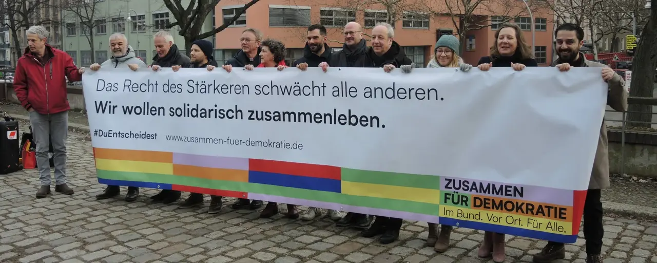 Eine Gruppe von Menschen hält ein Banner für die Kampagne #DuEntscheidest hoch.