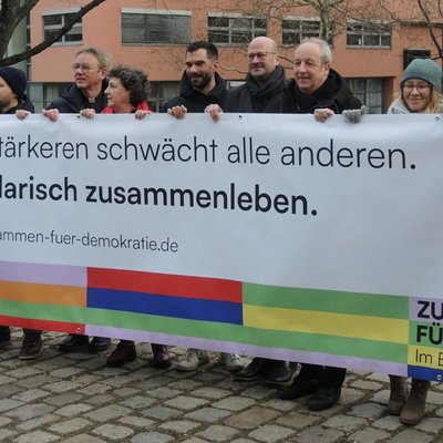 Eine Gruppe von Menschen hält ein Banner für die Kampagne #DuEntscheidest hoch.