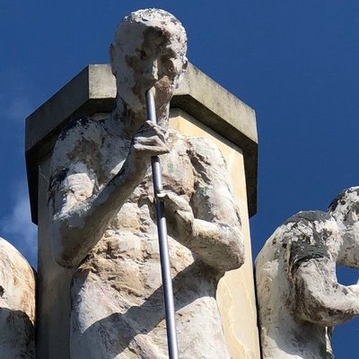 Figuren von Glasbläsern mit Werkzeug am Mund aus Sandstein ergeben den turmförmigen Glasmacherbrunnen in Weißwasser. 